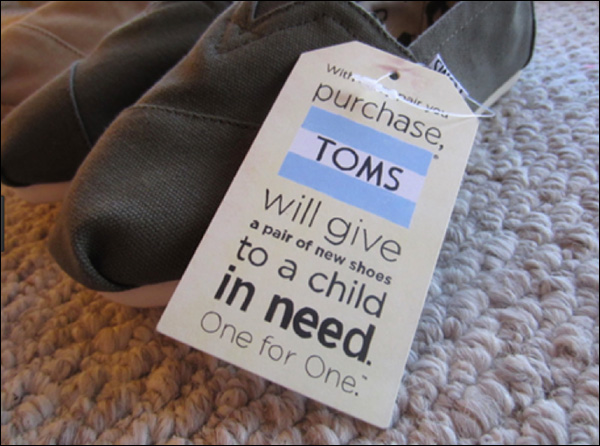 A pair of TOMS shoes with their pledge to donate to a child in need