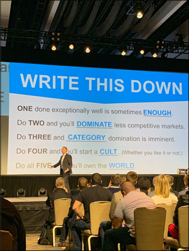 photo at a conference of speaker's presentation slide titled "write this down" 